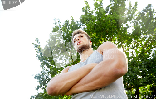 Image of sporty young man with crossed arms at summer park