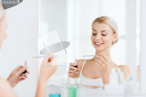 Image of woman with lipstick applying make up at bathroom