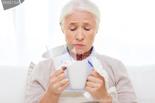 Image of sick senior woman drinking hot tea at home