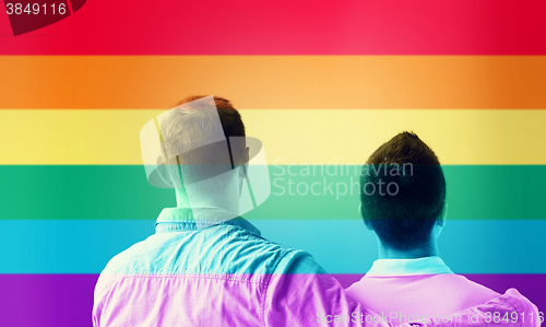 Image of close up of male gay couple over rainbow flag