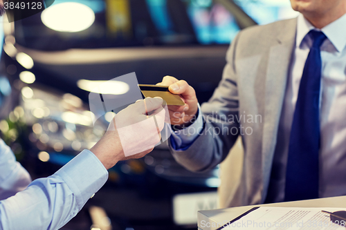 Image of customer giving credit card to car dealer in salon