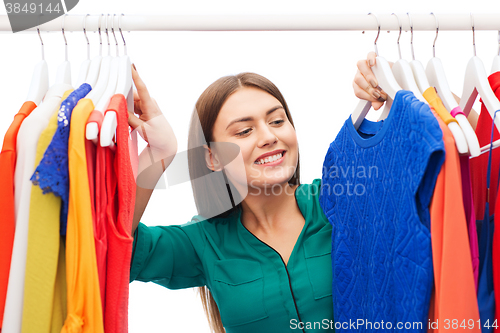 Image of happy woman choosing clothes at home wardrobe