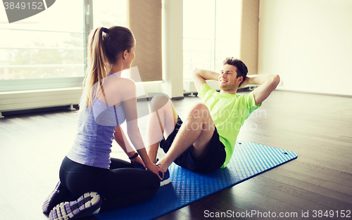 Image of woman with personal trainer doing sit ups in gym