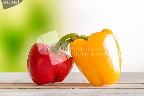 Image of Red and yellow pepper on a wooden table