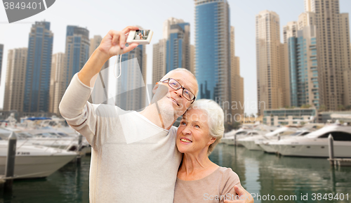 Image of senior couple taking selfie with camera at harbor