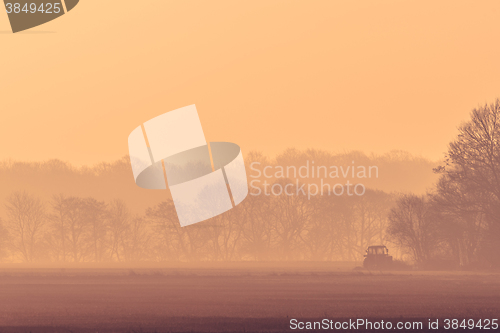 Image of Misty morning with a tractor on a field