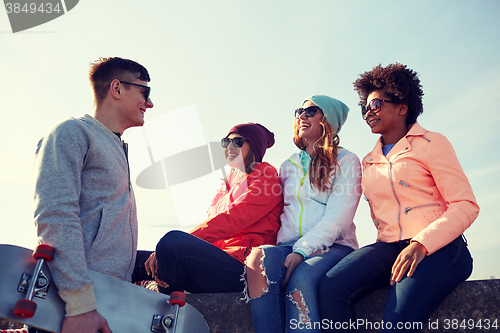 Image of happy teenage friends with skateboard on street