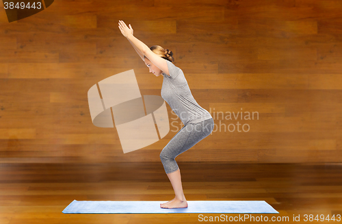 Image of woman making yoga in chair pose on mat