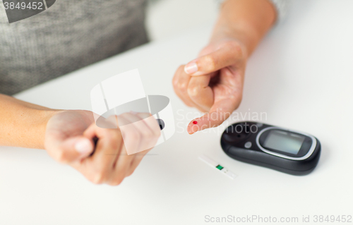 Image of close up of woman making blood test by glucometer