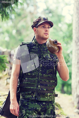 Image of young soldier with gun and flask in forest