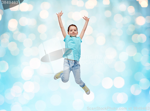 Image of happy little girl jumping in air over blue lights