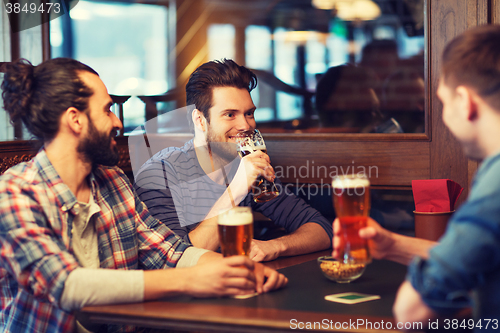 Image of happy male friends drinking beer at bar or pub