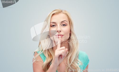 Image of beautiful young woman holding finger at her lips