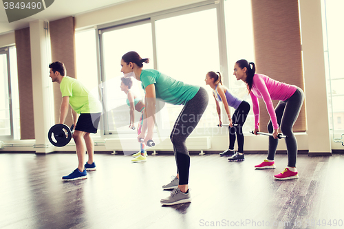 Image of group of people exercising with barbell in gym