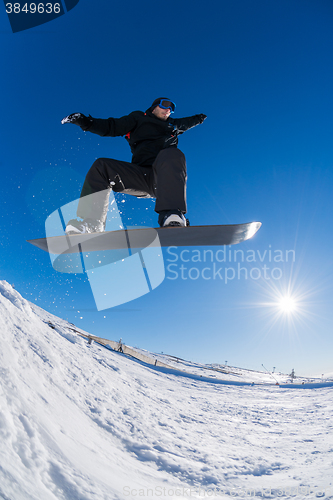 Image of Snowboarder jumping against blue sky