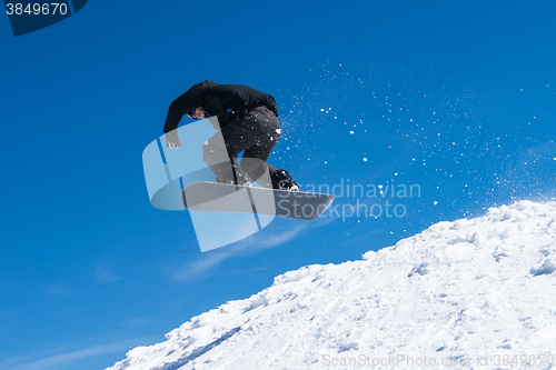 Image of Snowboarder jumping against blue sky