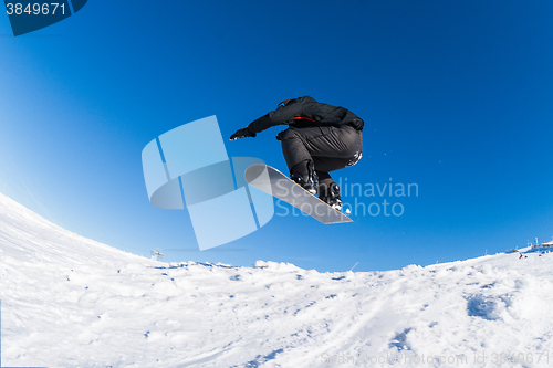 Image of Snowboarder jumping against blue sky