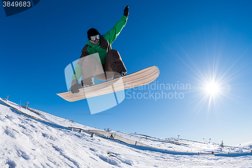 Image of Snowboarder jumping against blue sky