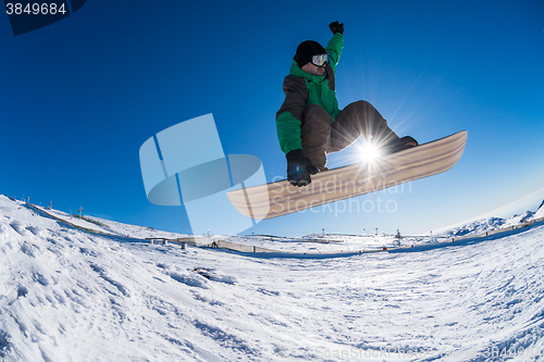 Image of Snowboarder jumping against blue sky