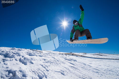 Image of Snowboarder jumping against blue sky