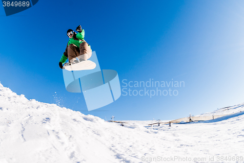 Image of Snowboarder jumping against blue sky