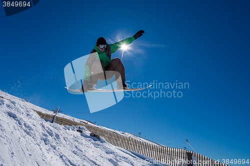 Image of Snowboarder jumping against blue sky