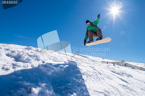 Image of Snowboarder jumping against blue sky