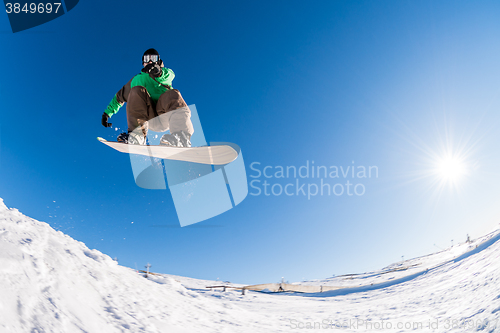 Image of Snowboarder jumping against blue sky