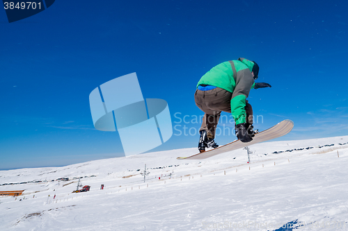 Image of Snowboarder jumping against blue sky