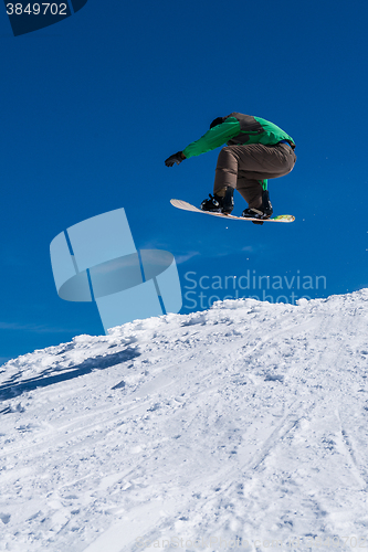 Image of Snowboarder jumping against blue sky