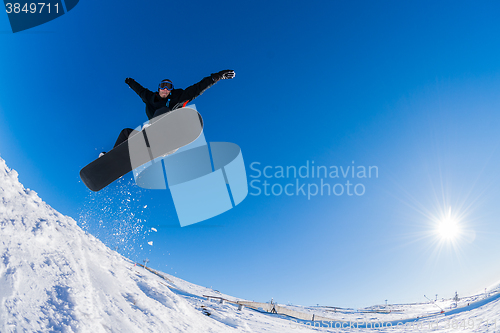 Image of Snowboarder jumping against blue sky