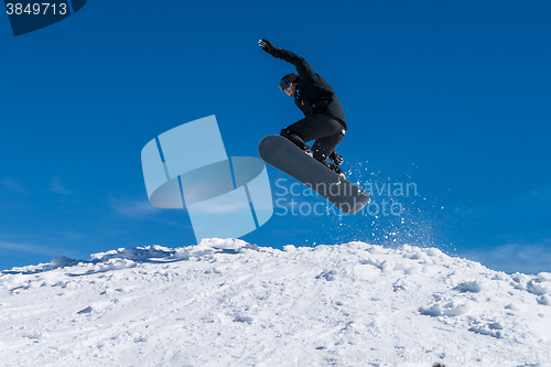 Image of Snowboarder jumping against blue sky