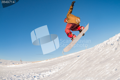 Image of Snowboarder jumping against blue sky