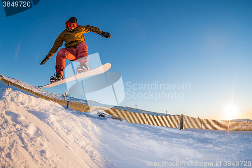 Image of Snowboarder jumping against blue sky