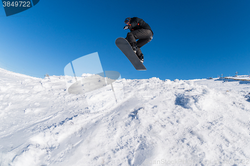 Image of Snowboarder jumping against blue sky