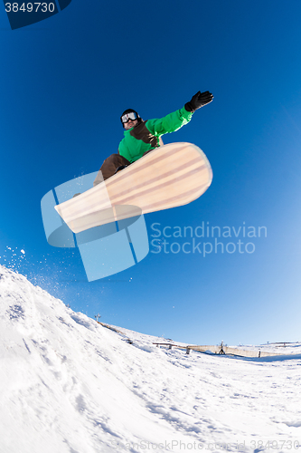 Image of Snowboarder jumping against blue sky