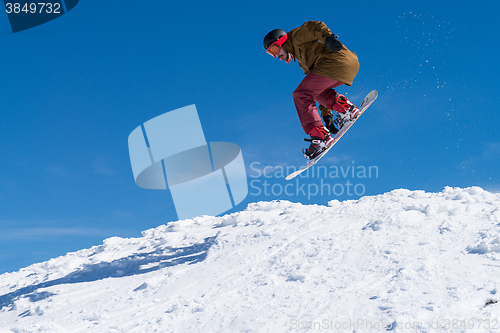 Image of Snowboarder jumping against blue sky