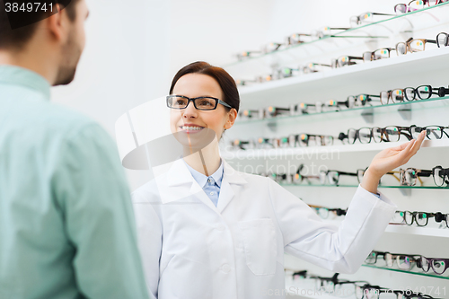 Image of optician showing glasses to man at optics store