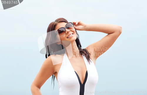 Image of smiling young woman with sunglasses on beach