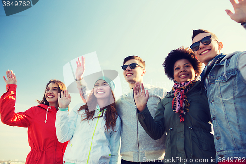 Image of happy teenage friends in shades waving hands