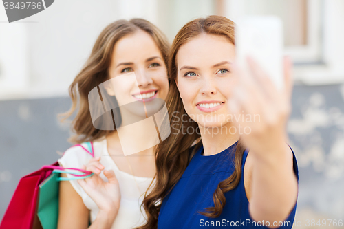 Image of happy women with shopping bags and smartphone