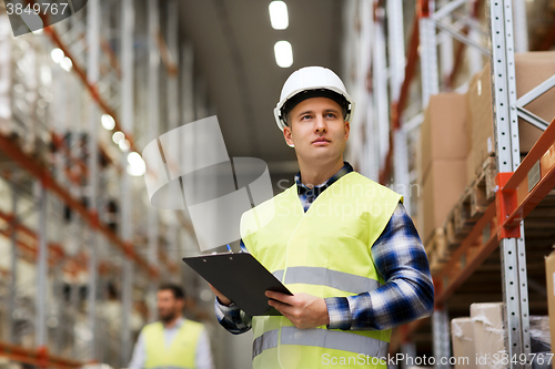 Image of man with clipboard in safety vest at warehouse