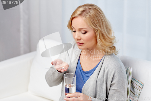 Image of woman with medicine and water glass at home