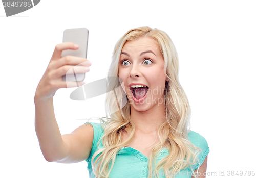 Image of smiling young woman taking selfie with smartphone