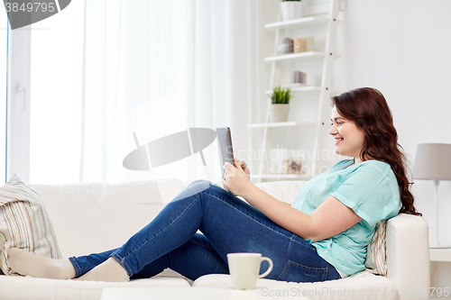 Image of happy young plus size woman with tablet pc at home