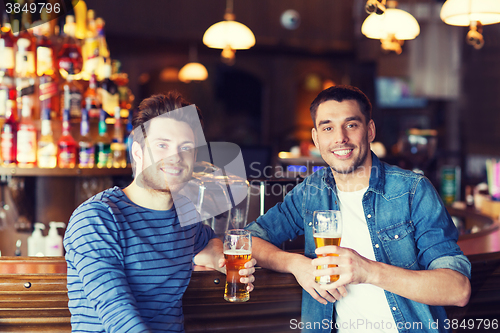 Image of happy male friends drinking beer at bar or pub