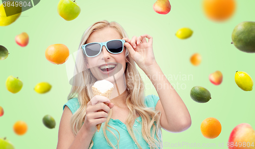 Image of happy young woman in sunglasses eating ice cream