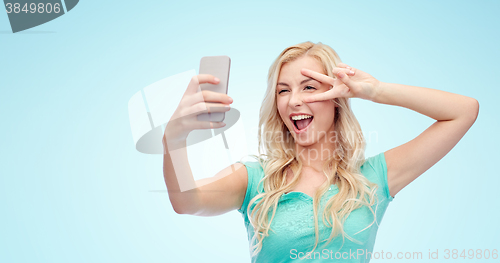 Image of smiling young woman taking selfie with smartphone