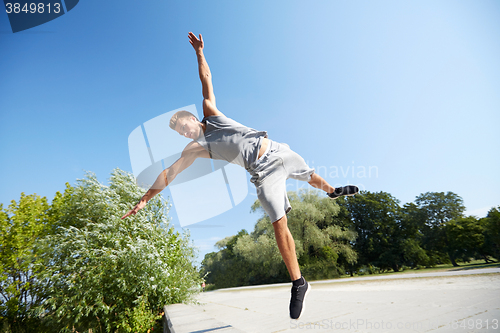 Image of sporty young man jumping in summer park