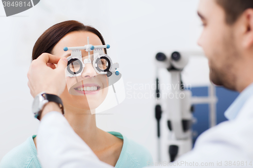 Image of optician with trial frame and patient at clinic